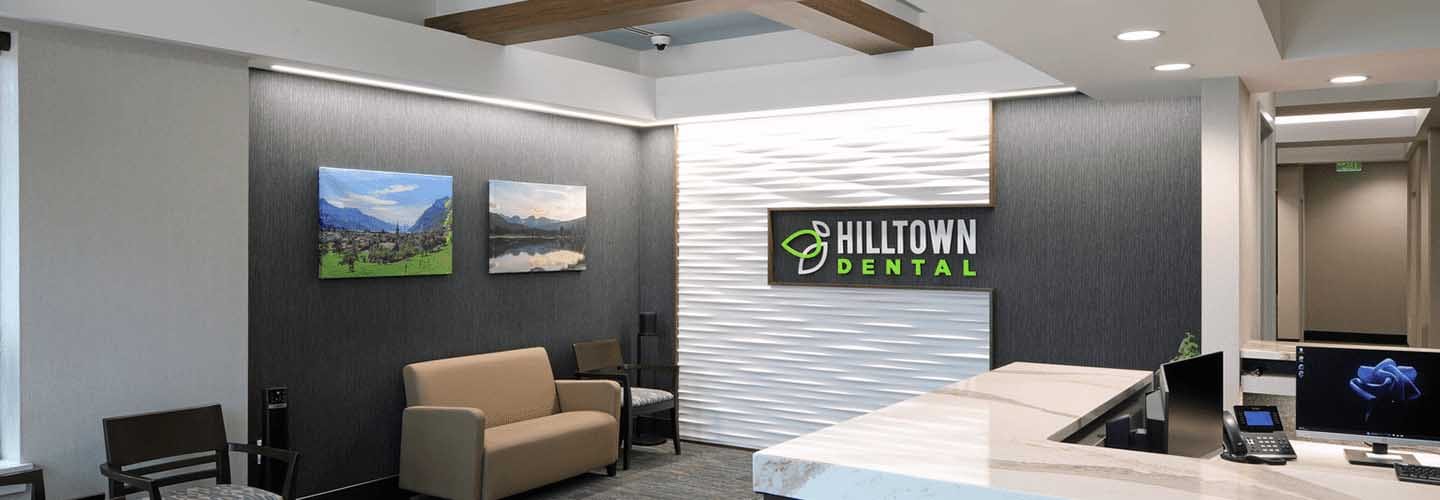 The durable but attractive finishes and textures, artwork, integrated lighting, and contemporary colors of a branded dental office of Hilltown Dental ChesterField, MO