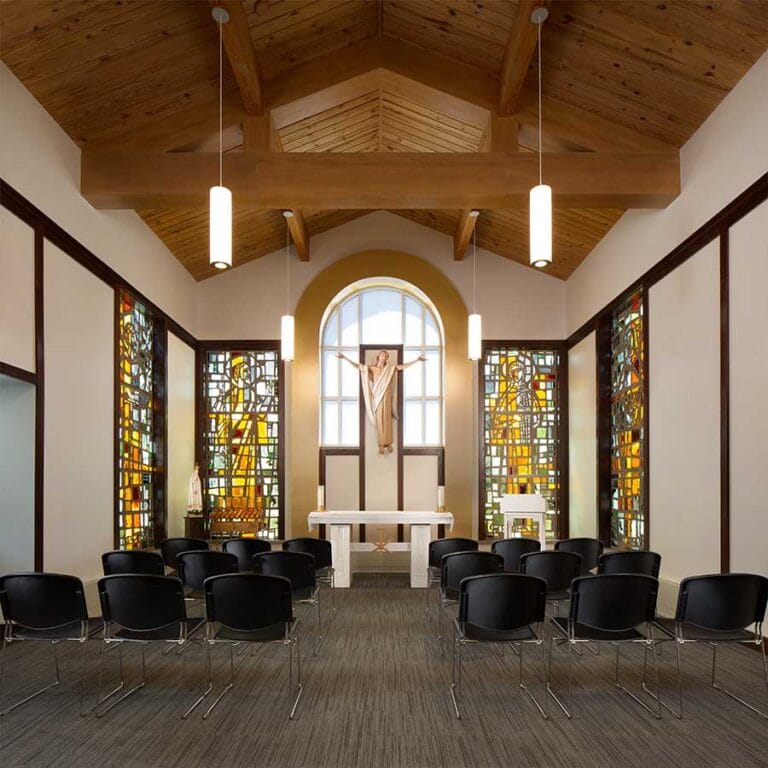 Adoration Chapel of Lumen Christi Catholic Church in Mequon, Wisconsin integrates warm light from stained glass and a statue of Jesus over the Alter